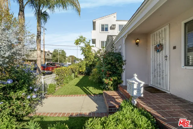 a view of a white house with a yard and potted plants