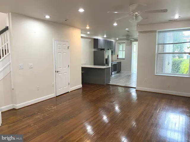 an open kitchen with white cabinets wooden floor and a refrigerator
