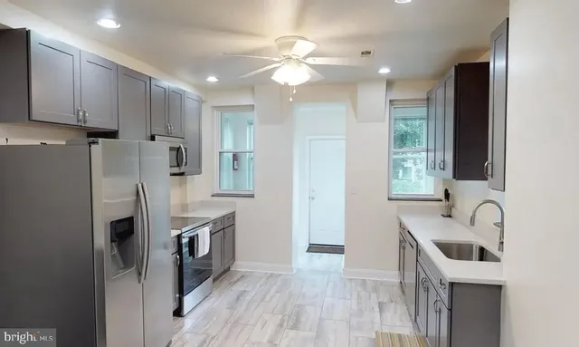 a kitchen with kitchen island granite countertop a sink stainless steel appliances and cabinets