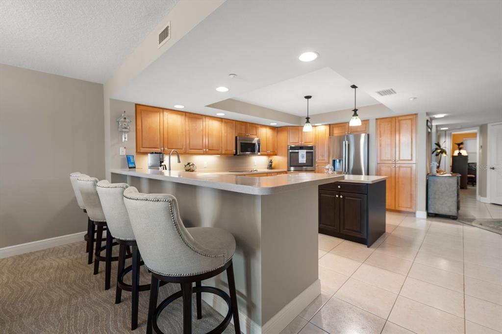 16326 Gulf Boulevard, Unit 206 Redington Beach, FL 33708 - Photo 15 of 42 a kitchen with stainless steel appliances kitchen island granite countertop a table chairs and a refrigerator