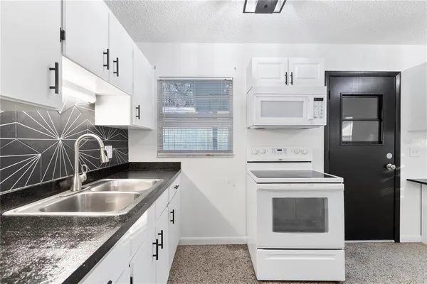 a kitchen with granite countertop a sink a stove and cabinets