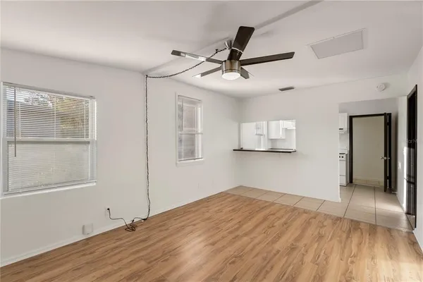 a view of empty room with wooden floor and fan