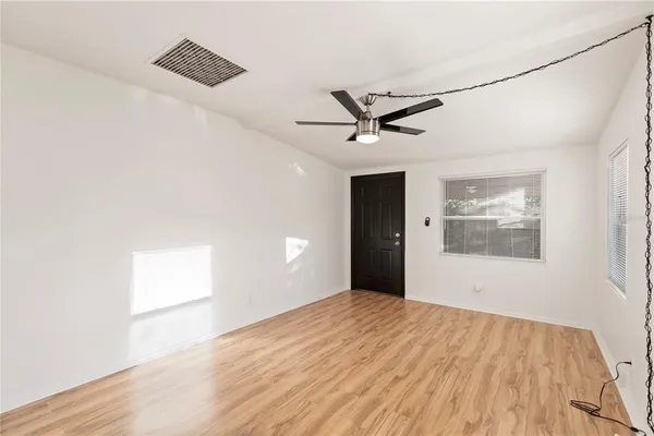 a view of an empty room with wooden floor and a window