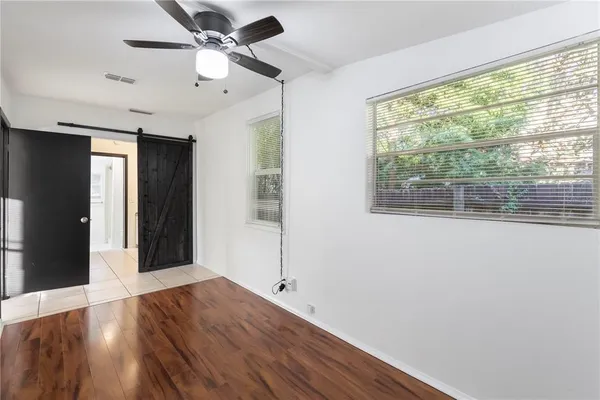 a view of an empty room with wooden floor and a window