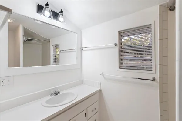 a bathroom with a sink vanity granite tub and a window