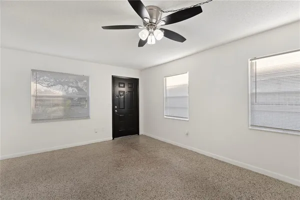 an empty room with windows and fan