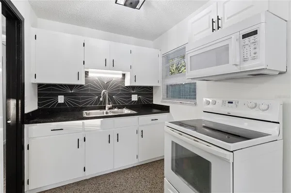 a kitchen with granite countertop white cabinets and white appliances