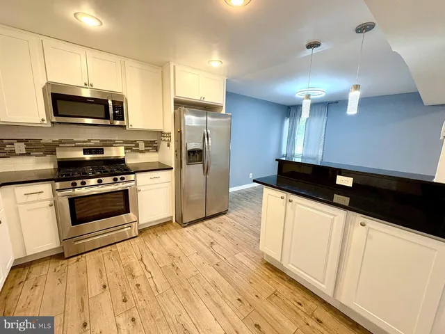 a kitchen with stainless steel appliances a stove a microwave and white cabinets