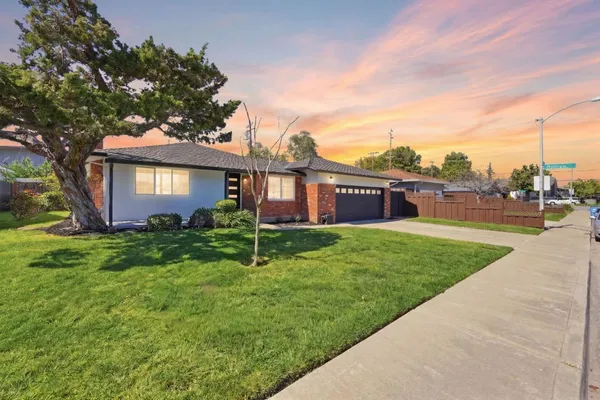 a view of a house with a big yard plants and large trees