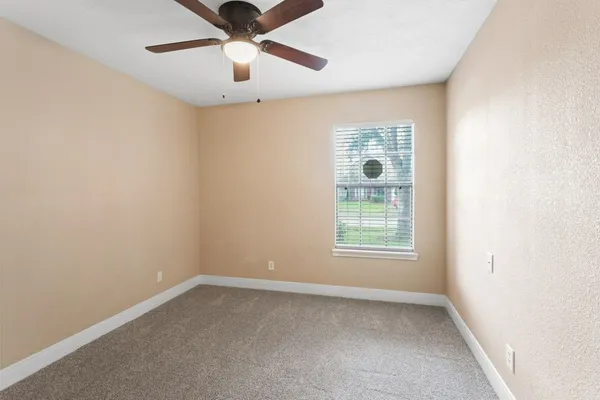an empty room with a window and a fan