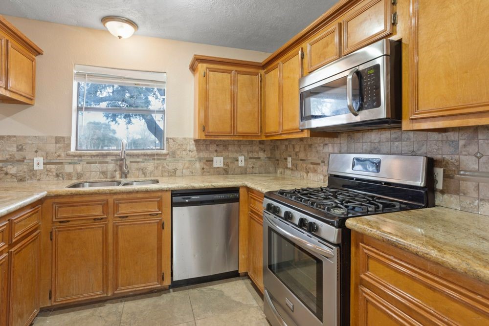 509 Teal Drive Dickinson, TX 77539 - Photo 7 of 23 a kitchen with stainless steel appliances granite countertop a stove a sink and a microwave