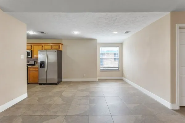 a view of a refrigerator in kitchen and an empty room