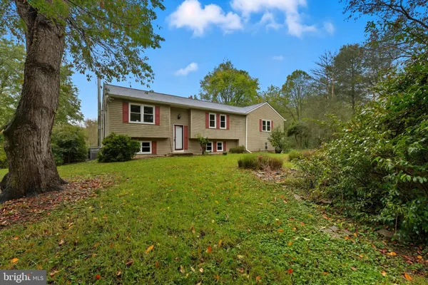 a view of a house with a big yard and large tree