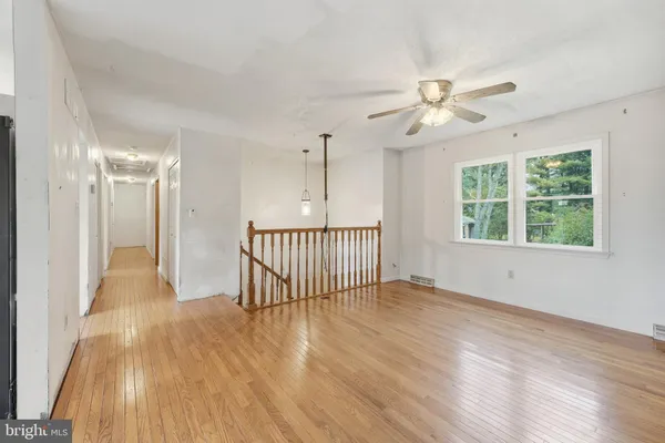 an empty room with wooden floor fan and windows