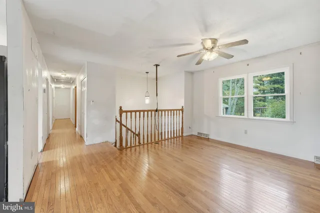 an empty room with wooden floor fan and windows
