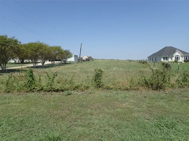 a view of a field with an ocean and trees