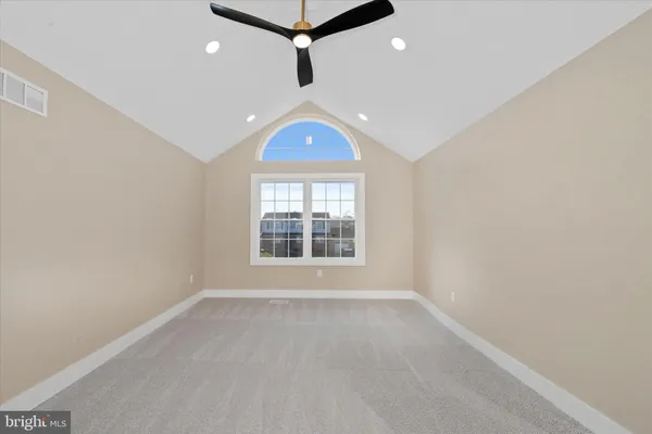 an empty room with ceiling fan and windows