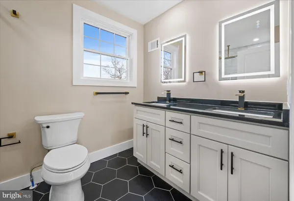 a bathroom with a granite countertop toilet sink and mirror