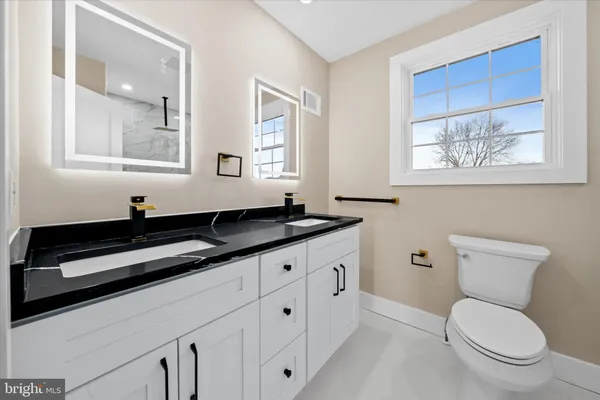a bathroom with a granite countertop toilet sink and mirror