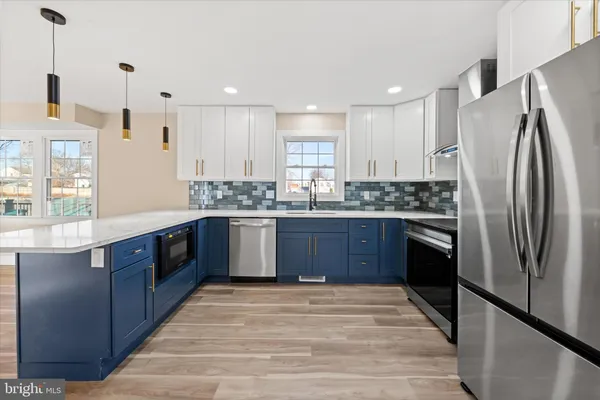 a large kitchen with stainless steel appliances granite countertop a stove a refrigerator and a sink with wooden cabinets