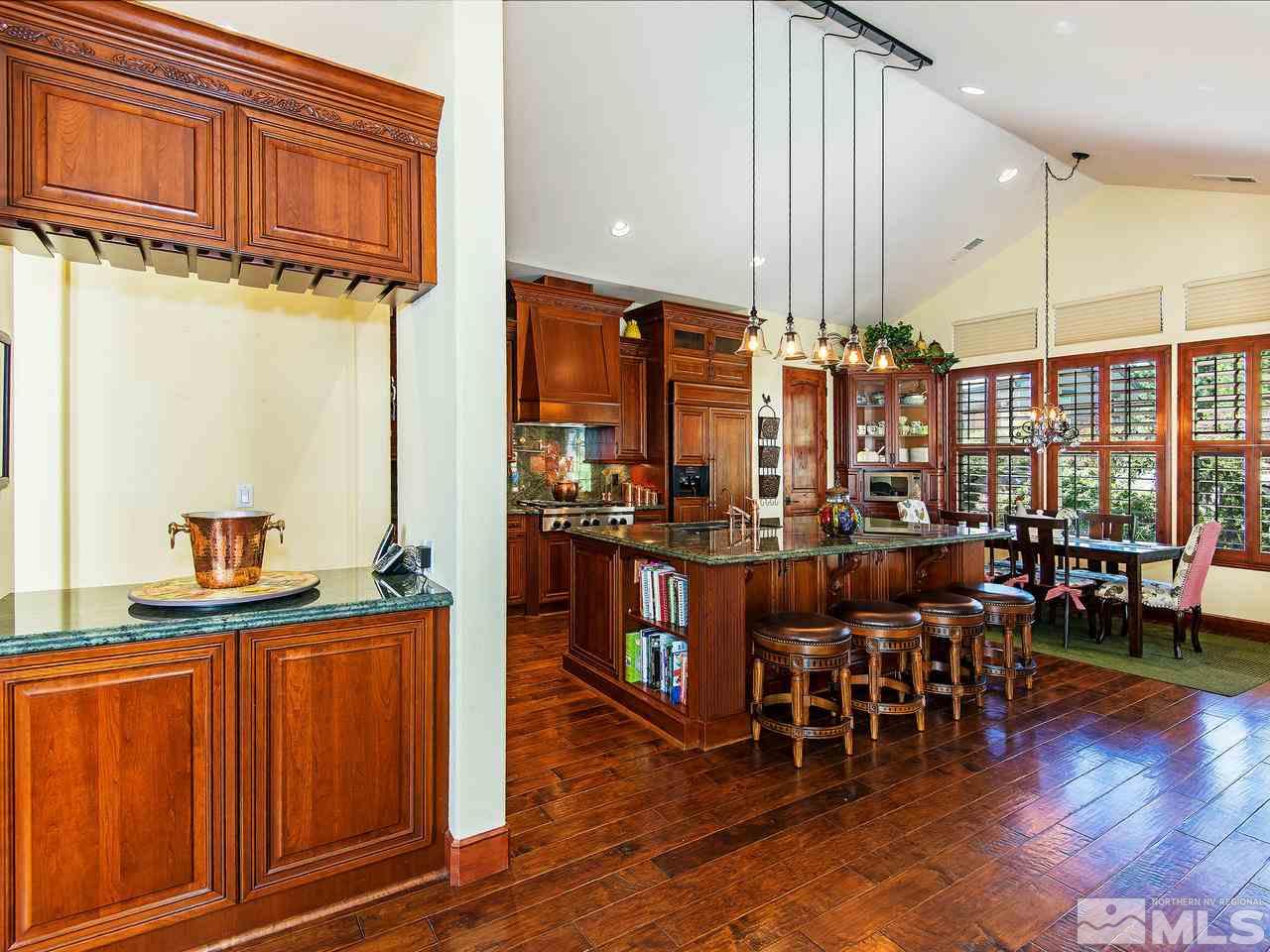 16885 Delacroix Reno, NV 89511 - Photo 9 of 25 a kitchen with stainless steel appliances kitchen island granite countertop a table chairs and a wooden floors