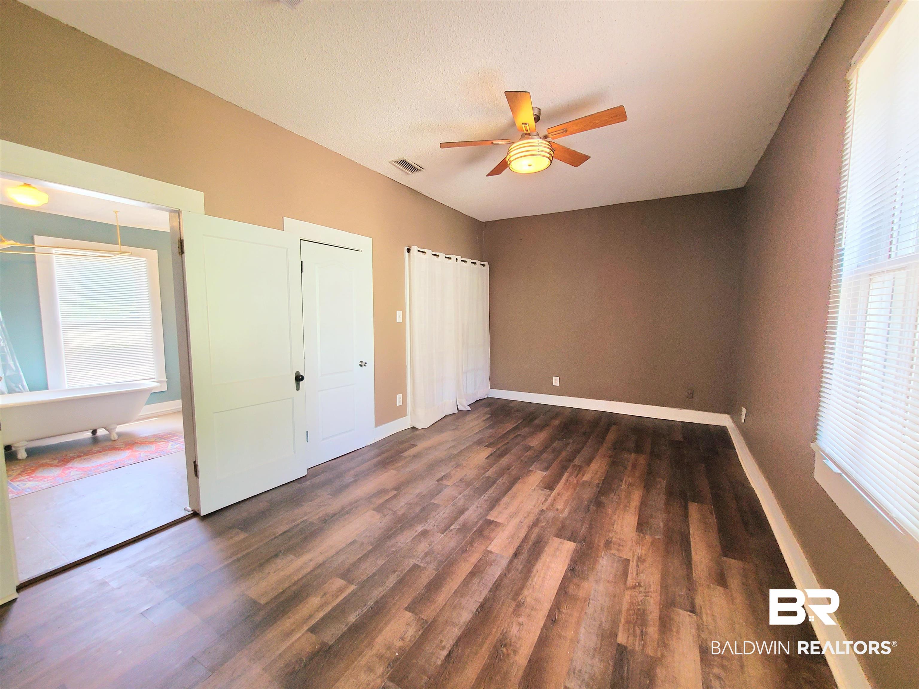 112 Espejo Street Mobile, AL 36604 - Photo 14 of 20 Unfurnished bedroom with dark wood-style floors, visible vents, a ceiling fan, and baseboards