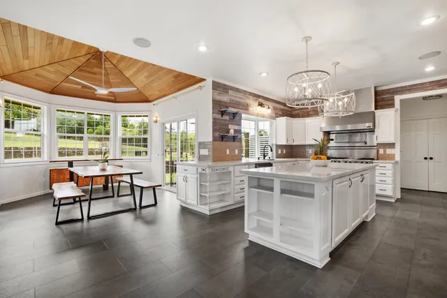 a kitchen with stainless steel appliances kitchen island granite countertop a stove and white cabinets