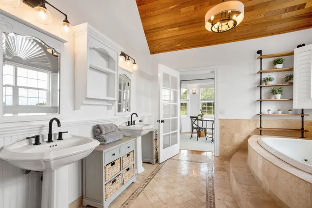 a bathroom with a sink a tub and a large mirror