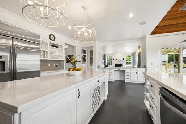 a kitchen with stainless steel appliances a white table chairs and a refrigerator