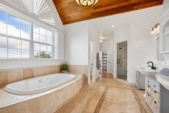 a bathroom with a tub a sink and a large window