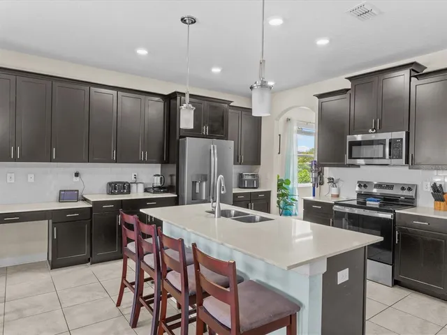 a kitchen with stainless steel appliances granite countertop a stove a refrigerator a sink a stove and chairs