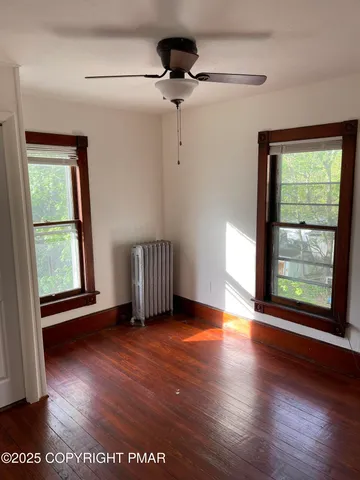 a view of an empty room with a window and wooden floor