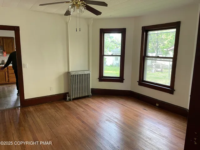 an empty room with wooden floor cabinet and windows