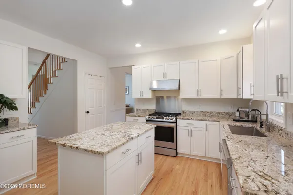a kitchen with granite countertop a sink stove and cabinets