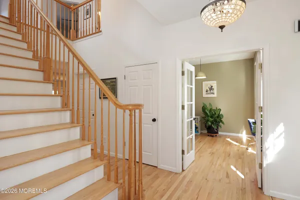 a view of a hallway to a livingroom with wooden floor and stairs