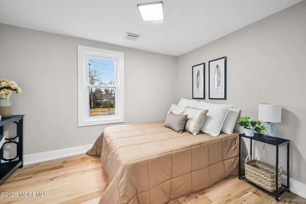 a bedroom with a bed potted plant on dresser and a wooden floor