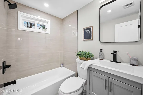 a bathroom with a sink a mirror a toilet and a bathtub