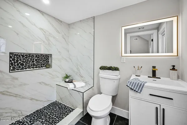 a bathroom with a granite countertop toilet sink and mirror