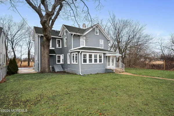 a view of a house with a big yard and large trees