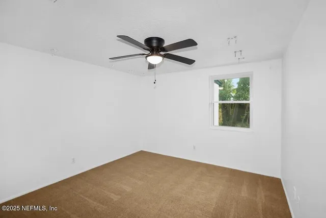 an empty room with a window and a fan