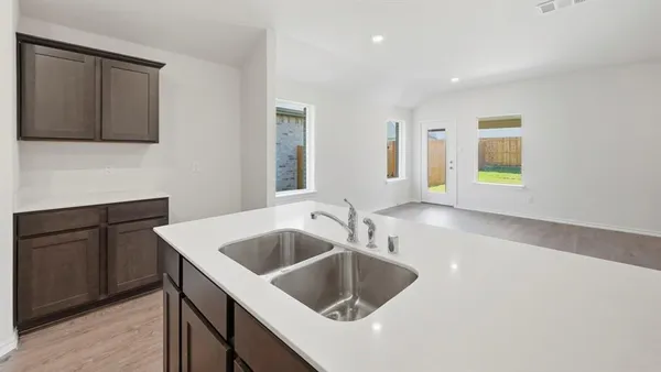 a kitchen with a sink and a stove top oven with wooden floor