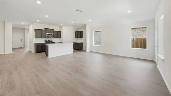 a large kitchen with stainless steel appliances kitchen island a large counter top and a wooden floors