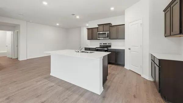 a kitchen with stainless steel appliances a stove top oven a sink a refrigerator white cabinets and wooden floor