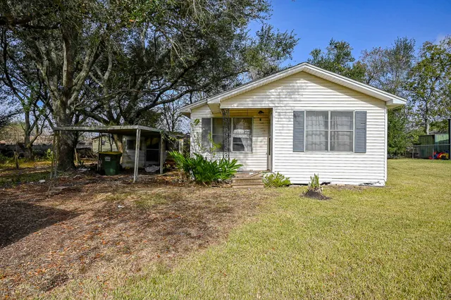 a front view of house with yard and trees in the background