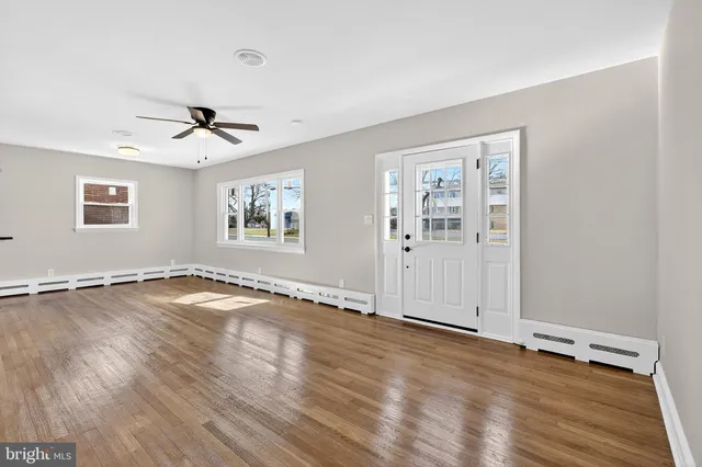 a view of an empty room with window and wooden floor
