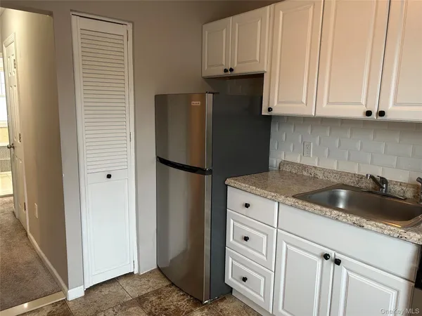 a kitchen with white cabinets and refrigerator
