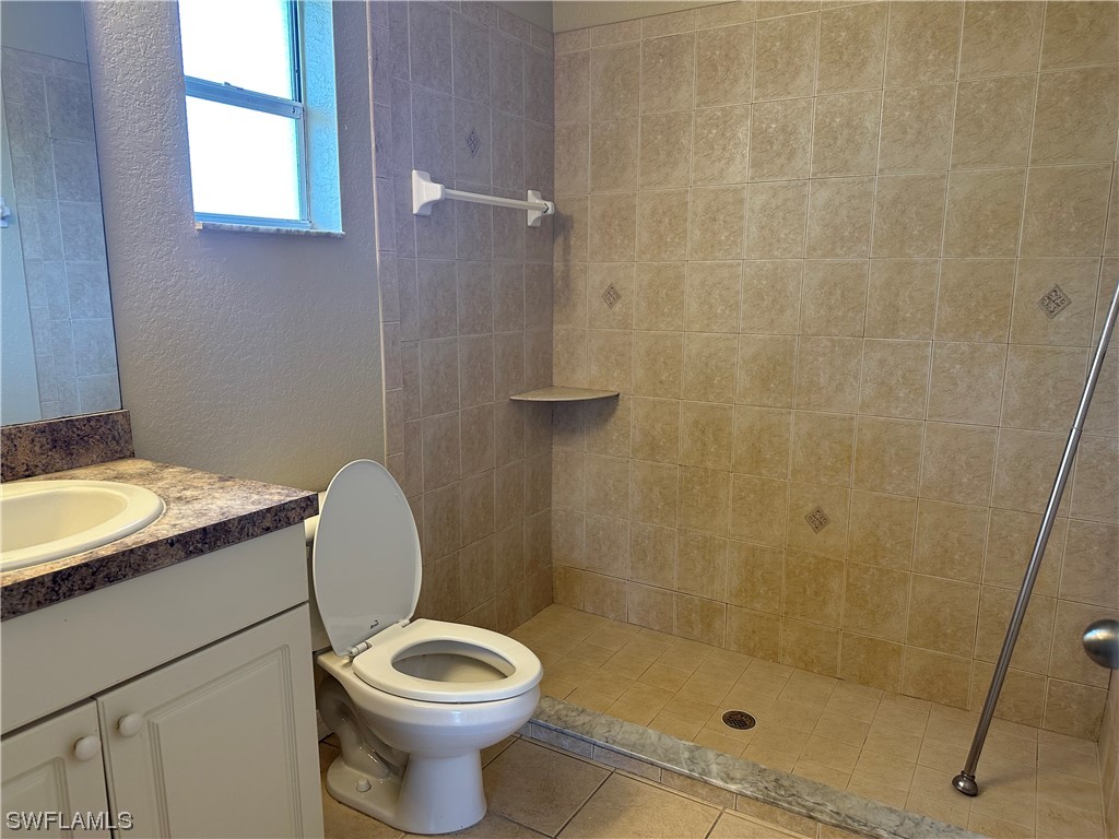 4106 24th Street Southwest Lehigh Acres, FL 33976 - Photo 15 of 15 a bathroom with a granite countertop toilet a sink and shower