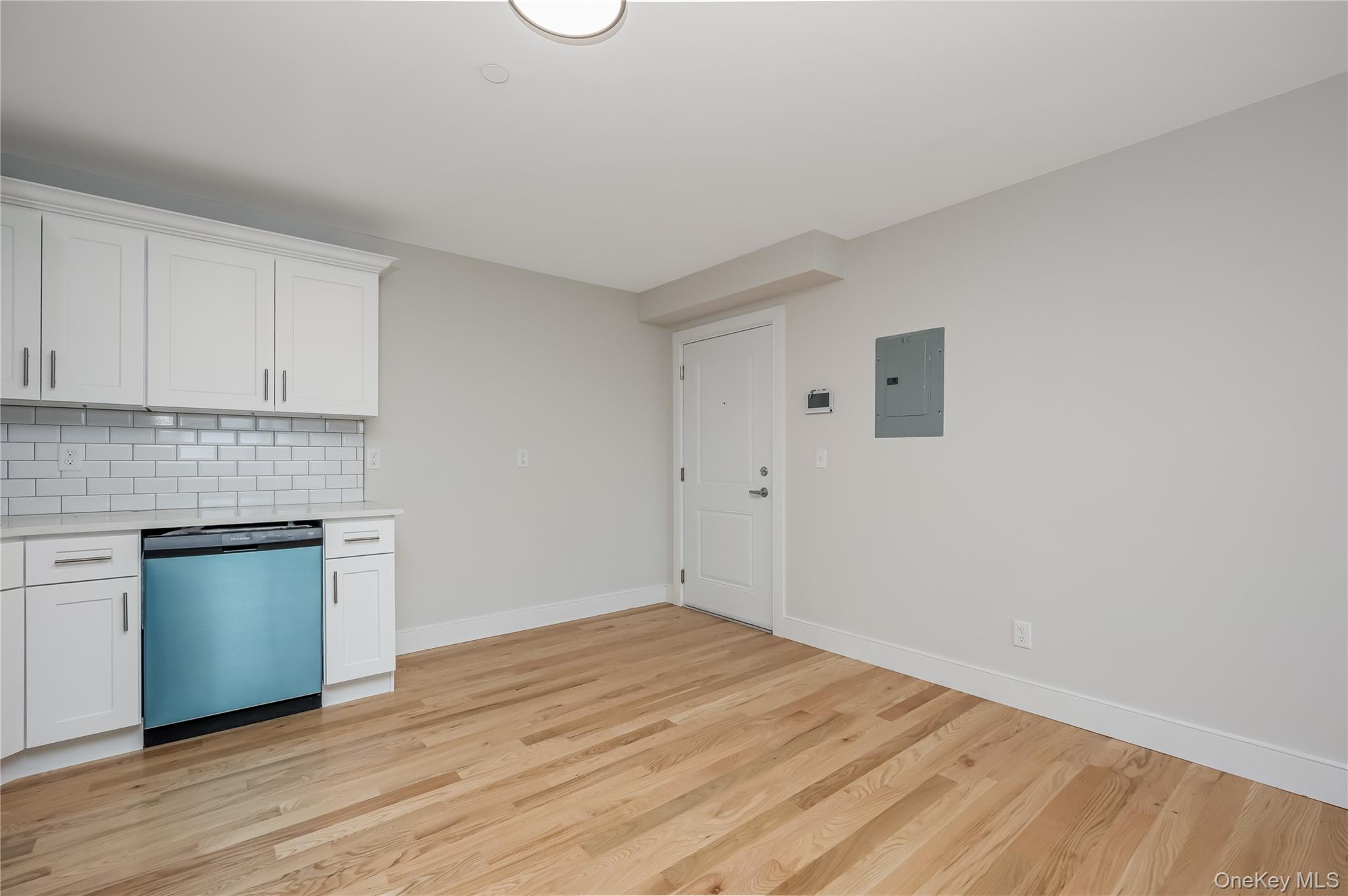 539 Front Street, Unit 4C Hempstead, NY 11550 - Photo 4 of 17 Kitchen with white cabinets, backsplash, dishwashing machine, and light wood-type flooring