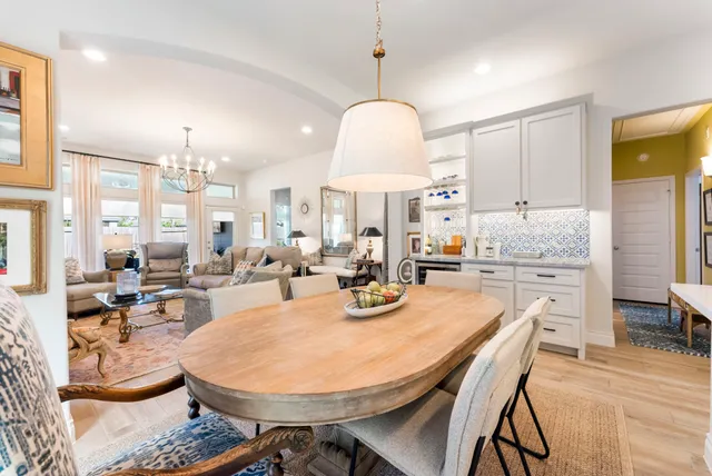 a very nice looking open dining room with kitchen island furniture a chandelier a large window and kitchen view