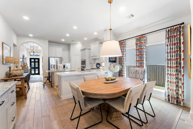 a view of a dining room and livingroom with furniture wooden floor a chandelier